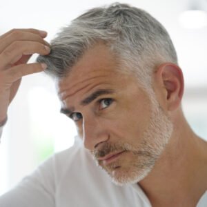 Hombre tocándose el cabello blanco. Dr. Holguera utiliza la mesoterapia como tratamiento capilar